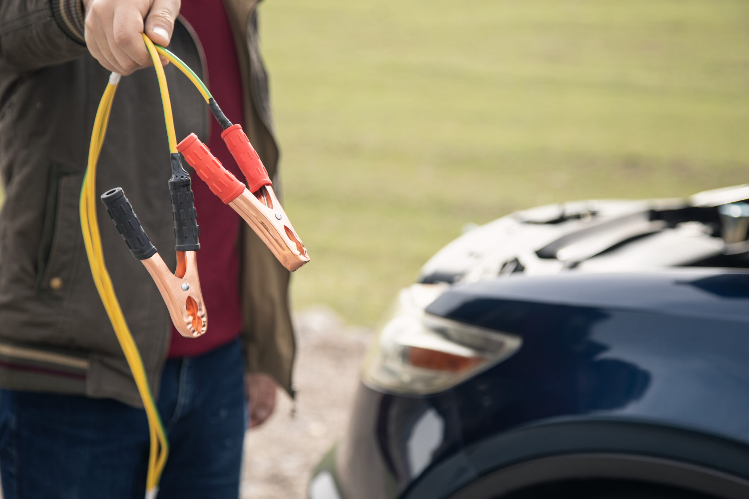 the man stops the car to jumper the battery